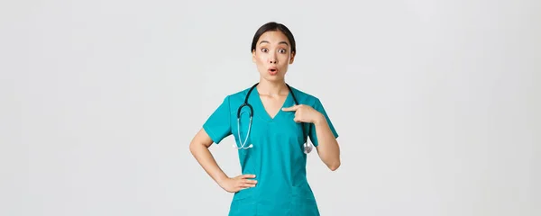 Covid-19, personnel de santé, concept pandémique. Surpris et embusqué asiatique femme médecin, infirmière dans les blouses pointant vers elle-même, beaing nommé ou choisi, debout fond blanc — Photo