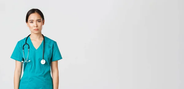 Covid-19, egészségügyi dolgozók, világjárvány. kimerült fiatal ázsiai női ápolónő, orvos keres fáradt után műszak a kórházban, néz szomorú fáradtság, álló fehér háttér ruhák — Stock Fotó