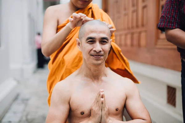 Close-up image of a handsome asian man is shaving hair by head of man who is ordained in Buddhism. — Zdjęcie stockowe