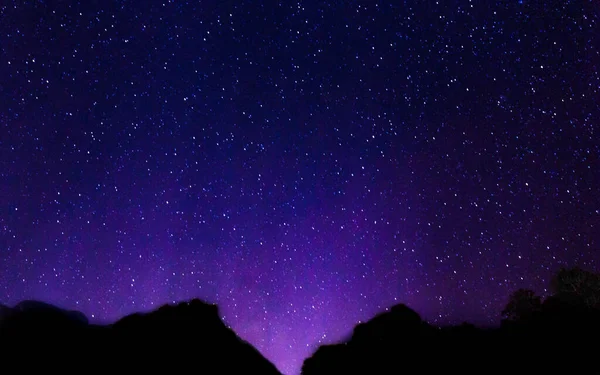 Cielo nocturno con muchas estrellas brillantes con fondo borroso de montaña . — Foto de Stock