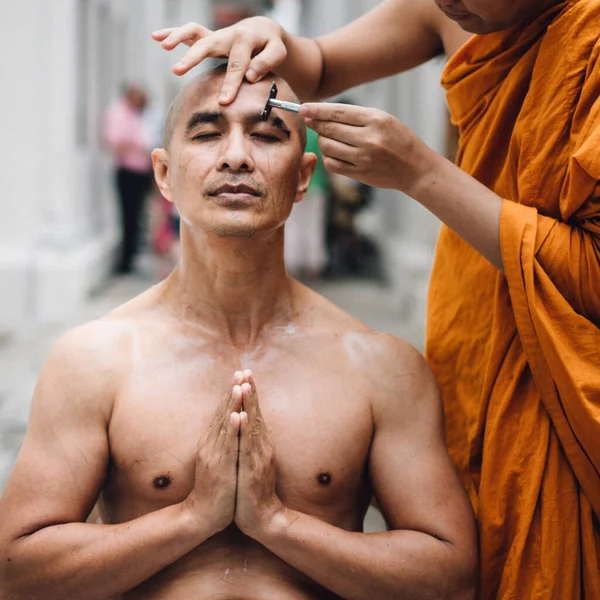 Close-up beeld van een knappe Aziatische man is scheren haar door hoofd van de man die is gewijd in het boeddhisme. — Stockfoto