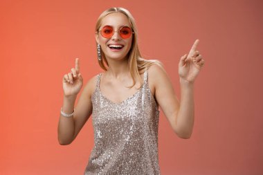Zarif, kaygısız, harika, sarışın, gümüş elbiseli, kırmızı güneş gözlüklü, neşeli bir şekilde dans eden, dans pistinde dans eden, gülümseyen, eğlenen, eğlenen, eğlenen, vakit geçiren arkadaşlar, stüdyo arkaplanı.