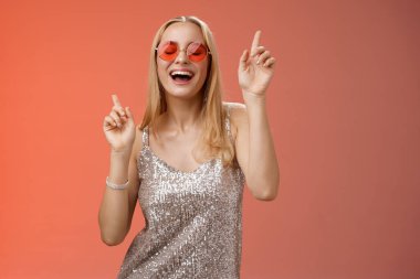 Eğlenceli, mutlu, güler yüzlü, gece kulübünde dans eden, eğlenen, çılgın partiler veren, şık kıyafetler giyen, güneş gözlüklü, gülümseyen ve şarkı söyleyen bir kadın.