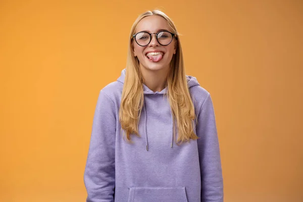 Весела чарівна жінка-програмістка весело показує язик дурень навколо колег під час обідньої перерви, посміхаючись широко сміється в милих окулярах фіолетовий светр, стоїть фіолетовий фон — стокове фото