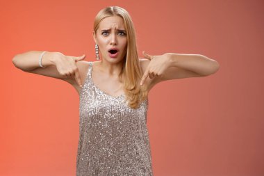 Hayal kırıklığına uğramış, gümüş elbiseli, sarışın, zarif kız arkadaşı kandırmış, suratını buruşturmuş, hoşnutsuz, internetten alınmış ayakkabıları gösterme zahmetine girmiş, kıyafetleri eşleşmiyor, mutsuz duruyor.