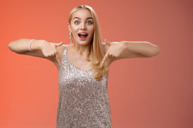 Etkilenmiş, çekici, çekici, pırıl pırıl, parlak elbiseli, nefes nefese kalmış, kamerayı aşağıya çevirerek heyecanlanan çekici, çekici, çekici, çekici, sarışın kız.