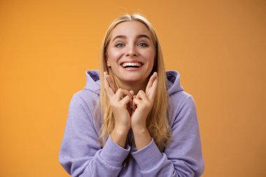 Şanslı, iyimser, pozitif, gülümseyen, mutlu, mutlu, sarışın kız parmaklarını çapraz yapıp dilek tutuyor. Dilek tutkuları gerçekleşiyor.