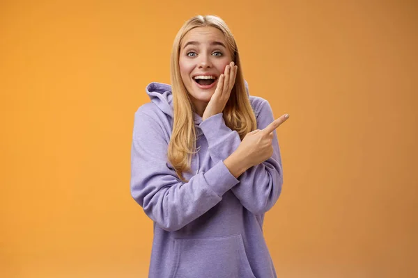 Διασκεδαστικό ενθουσιασμένοι άφωνος ευτυχισμένη νεαρή ξανθιά γυναίκα 25 σε hoodie δεν μπορεί να πιστέψει ευτυχία τύχη δείχνει δεξιά έκπληκτος χαμογελώντας ευρέως αφής μάγουλο έκπληκτος λάβετε φοβερό απροσδόκητο δώρο — Φωτογραφία Αρχείου
