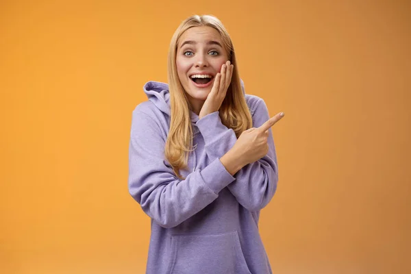 Divertido excitado sin palabras feliz joven rubia mujer 25s en sudadera con capucha no puede creer suerte felicidad apuntando derecho sorprendido sonriendo ampliamente tocar mejilla sorprendido recibir impresionante regalo inesperado —  Fotos de Stock