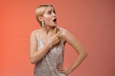 Şok olmuş, gümüşten parıltılı elbisesi olan, rahatsız edici, sarışın, çekici bir kadın sağ üst köşeden dönüyor. Şikayet eden garip bir ses geliyor.