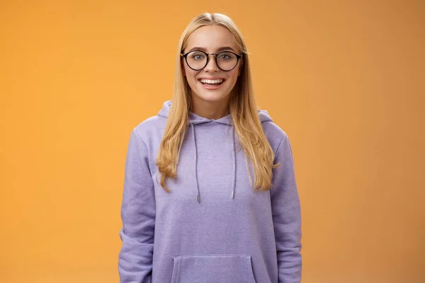 Encantadora estudiante geek sonriendo energizado quiere participar evento universitario sonriendo mirada emocionada usando gafas sudadera con capucha púrpura de pie divertido fondo naranja divertirse —  Fotos de Stock
