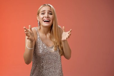 Paniğe kapılmış, kalbi kırık, ağlayan, el kaldıran, ayrıImamış erkek arkadaşına yalvaran, üzgün, harap olmuş, kırmızı arka planda duran, üzgün, üzgün bir kız.