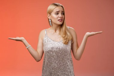 Endişeli, kendine güveni olmayan, tatlı sarışın kız kendini kaybolmuş hissediyor omuz silkiyor, kararları tartıyor, doğru görünüyor.