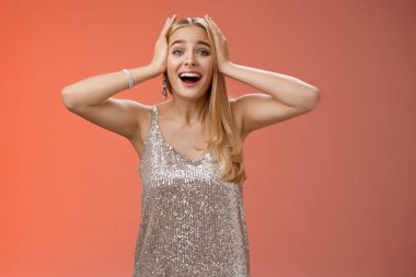 Şaşırmış, heyecanlı, gümüş renkli şık elbiseli sarışın kadın kendi şansına inanamıyor. Mutluluk el ele tutuşuyor. Gülümsüyor, haykırıyor, hayrete düşürüyor.