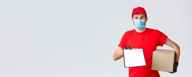 Paketler ve paket teslimatı, karantina teslimatı, nakil emirleri. Kırmızı üniformalı arkadaş canlısı kurye, yüz maskesi ve eldiven, paket kutusu ve dosya sipariş formunu istemciye ver