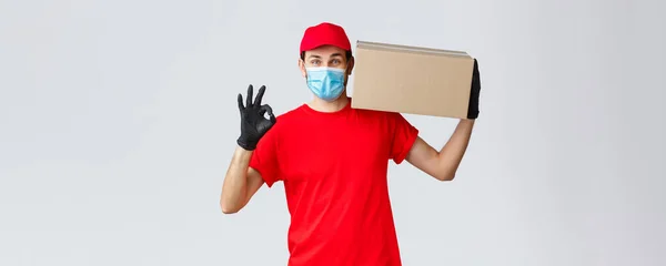 Packages and parcels delivery, covid-19 quarantine delivery, transfer orders. Courier service of express delivery, hold box on shoulder make okay sign, no problem, guarantee safe buying and shipping — Stock Photo, Image