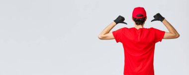 Covid-19, kendini karantina, online alışveriş ve nakliye konsepti. Posta şirketinin logosunu göstermek için kuryenin tişörtünü göstermesi, Coronavirus sırasında teslimat servisini teşvik etmesi.