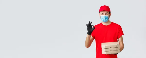 Food delivery, application, online grocery, contactless shopping and covid-19 concept. Courier guarantee quality of pizza, holding boxes, showing okay sign in recommendation or approval, wear mask — Stock Photo, Image