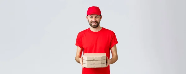 Essenslieferung, Quarantäne, zu Hause bleiben und Online-Bestellung. Freundlich lächelnder Kurier in roter Uniform, der Kundenauftrag erteilt. Angestellter bringt Pizza ins Haus, grauer Hintergrund — Stockfoto