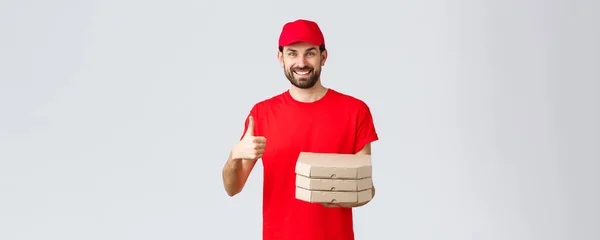 Essenslieferung, Quarantäne, zu Hause bleiben und Online-Bestellung. Freundlich lächelnder bärtiger Kurier in roter Uniformmütze und T-Shirt, empfiehlt Service oder Restaurant, schenkt Pizza an Kunden — Stockfoto