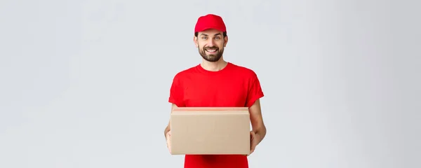 注文配達、オンラインショッピングとパッケージ配送の概念。笑顔フレンドリーな宅配便は、クライアントの玄関先にパッケージをもたらす.赤のサービスキャップとTシャツ保持ボックス、顧客のための小包の従業員 — ストック写真