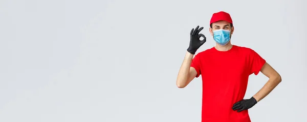 Covid-19, self-quarantine, shopping concept. Courier have no problem delivering your packages, food from shops to house during coronavirus, wear face mask and gloves, delivery guy show ok — Stock Photo, Image