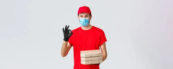 Food delivery, application, online grocery, contactless shopping and covid-19 concept. Courier guarantee quality of pizza, holding boxes, showing okay sign in recommendation or approval, wear mask — Stock Photo, Image