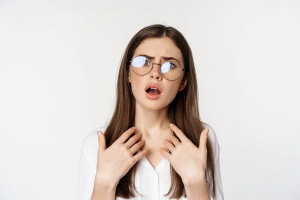 Offended and upset young woman in glasses, beeing jealous or disappointed, feeling hurt, grimacing and sulking, standing confused over white background — Stock Photo, Image