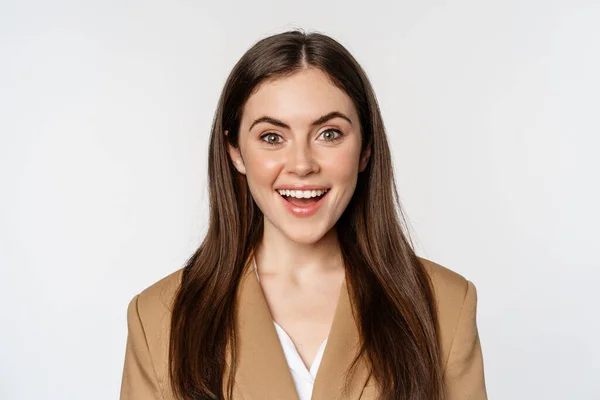 Close up portrait of enthusiastic corporate woman, looking amazed and excited at camera, standing in suit over white background — Stock fotografie