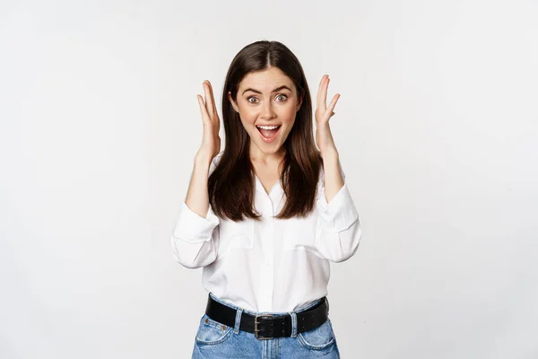 Excited young adult woman reacting to win, surprise news, screaming and cheering, triumphing, achieve goal and celebrating, standing over white background — Fotografia de Stock