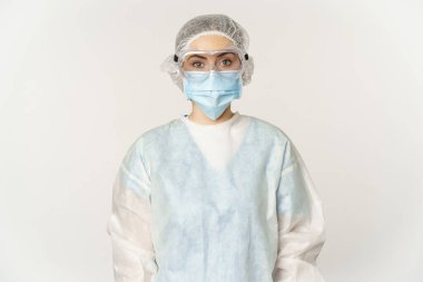 Portrait of doctor, female nurse in personal protective equipment, looking confident and professional, standing over white background