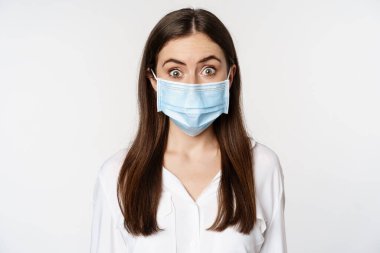 Covid-19 and pandemic concept. Young office woman wearing medical mask during coronavirus social distancing, standing over white background