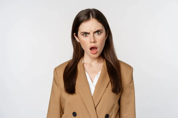 Frustrated, insulated woman in business outfit, staring startled and shocked at camera, standing over white background — Stock fotografie