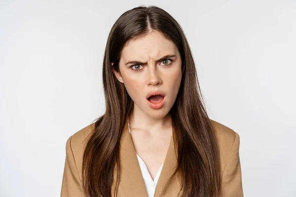 Confused office worker, businesswoman staring shocked and insulted at camera, standing over white background — Stock fotografie