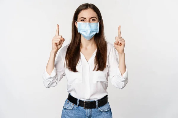 顔の医療マスク中の企業の女性の肖像コロナウイルスから,指を指して,広告を表示,白の背景 — ストック写真