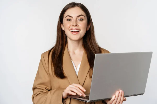 Портрет корпоративної жінки, що працює з ноутбуком, посміхається і виглядає наполегливо, білий фон — стокове фото