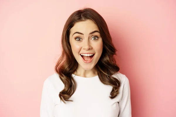 Close up of enthusiastic brunette girl with makeup, smiling and looking happy at camera, posing against pink background — ストック写真