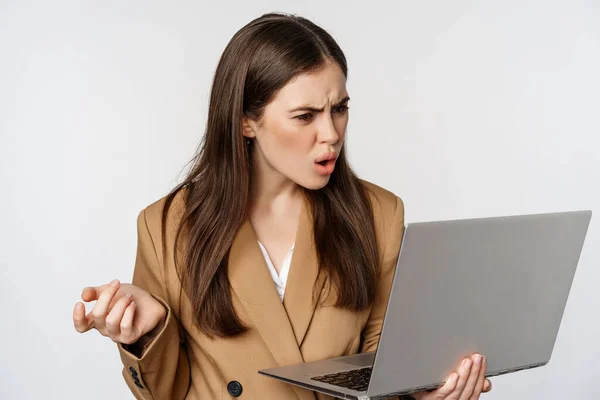 Mulher de negócios chocada e desapontada olhando para a tela do laptop com expressão facial ofendida e frustrada, de pé contra fundo branco — Fotografia de Stock