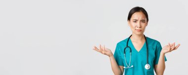 Sağlık çalışanları, virüsü önleme, karantina kampanyası konsepti. Kafası karışık ve kafası karışık Asyalı kadın doktorların yakın plan çekimleri karmaşık bir sorun yaşıyor, el kaldırıyor ve omuz silkiyor