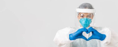 Covid-19, koronavirüs hastalığı, sağlık çalışanları konsepti. Kişisel koruma ekipmanlarıyla kendinden emin ve ilgili Asyalı kadın doktorların yakın çekimi hastalara kalp hareketi gösteriyor.