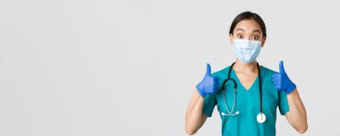 Covid-19, koronavirüs hastalığı, sağlık çalışanları konsepti. Gülen Asyalı doktor, tıbbi maske takan doktor ve lastik eldiven takan, iyi iş çıkardığını gösteren, onaylayan, öven.