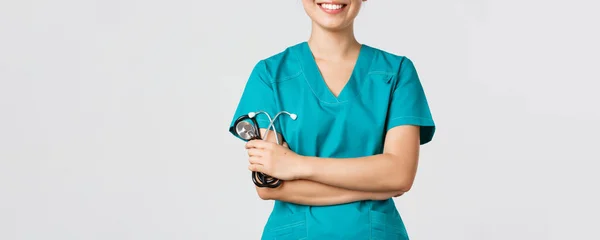 Covid-19, maladie du coronavirus, concept des travailleurs de la santé. Plan recadré de femme asiatique médecin corps souriant, bras croisés poitrine confiante et tenant stéthoscope, debout fond blanc — Photo