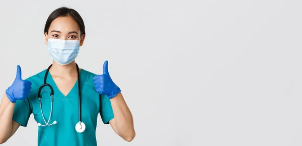 Covid-19, coronavirus disease, healthcare workers concept.有自信的亚洲医生，戴着医疗面罩和橡胶手套的护士，大拇指翘得高高在上，提供服务，具备良好的背景 — 图库照片