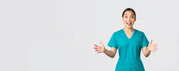 Covid-19, trabajadores de la salud, concepto pandémico. Feliz y sorprendida enfermera asiática en matorrales levantando las manos emocionada y sonriente. Doctor felicitar con grandes noticias, aplausos, fondo blanco — Foto de Stock