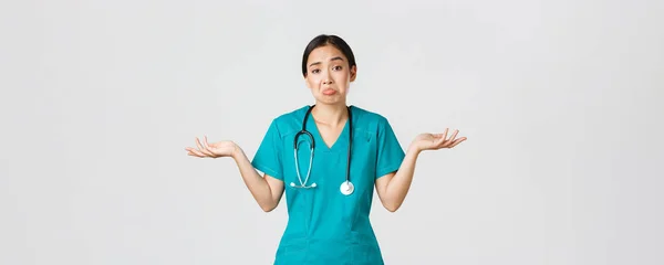 Covid-19, pracownicy służby zdrowia, koncepcja pandemii. Portret bezwskazówki azjatyckiej pielęgniarki, kobieta lekarz wzrusza ramionami i rozkłada ręce bokiem nieświadomy, nie wiem, nie może pomóc, białe tło — Zdjęcie stockowe