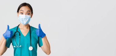 Covid-19, koronavirüs hastalığı, sağlık çalışanları konsepti. Gülen Asyalı doktor, tıbbi maske takan doktor ve lastik eldiven takan, iyi iş çıkardığını gösteren, onaylayan, öven.