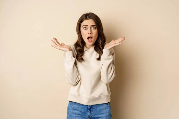 Shocked girl looking startled at camera, drop jaw and spread hands sideways in questioned and stunned face expression — Foto Stock