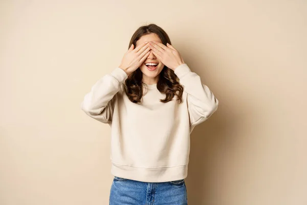 Excited happy girl smiling, close eyse and wait for surprise gift, standing blinsided over beige background — Stock Photo, Image