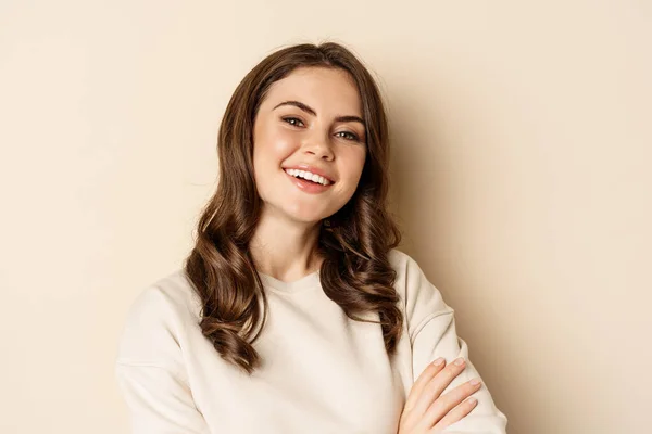 Close up portrait of young caucasian woman with dark hair, smiling white teeth, laughing, posing carefree against beige background — Fotografia de Stock