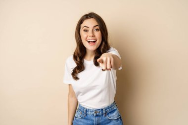 Bu sensin, tebrikler. Gülümseyen güzel bir kadın kamerayı işaret ediyor, seni tebrik ediyor, övüyor, bej arka planda duruyor.